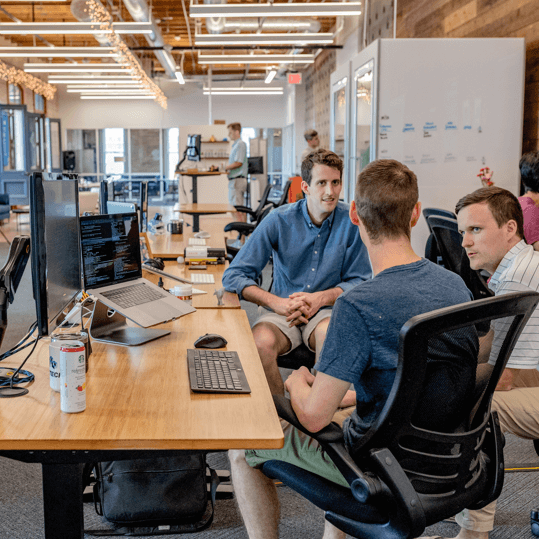 Professional team collaborating and discussing project details in a modern office setting, representing the services offered by Techwink Services